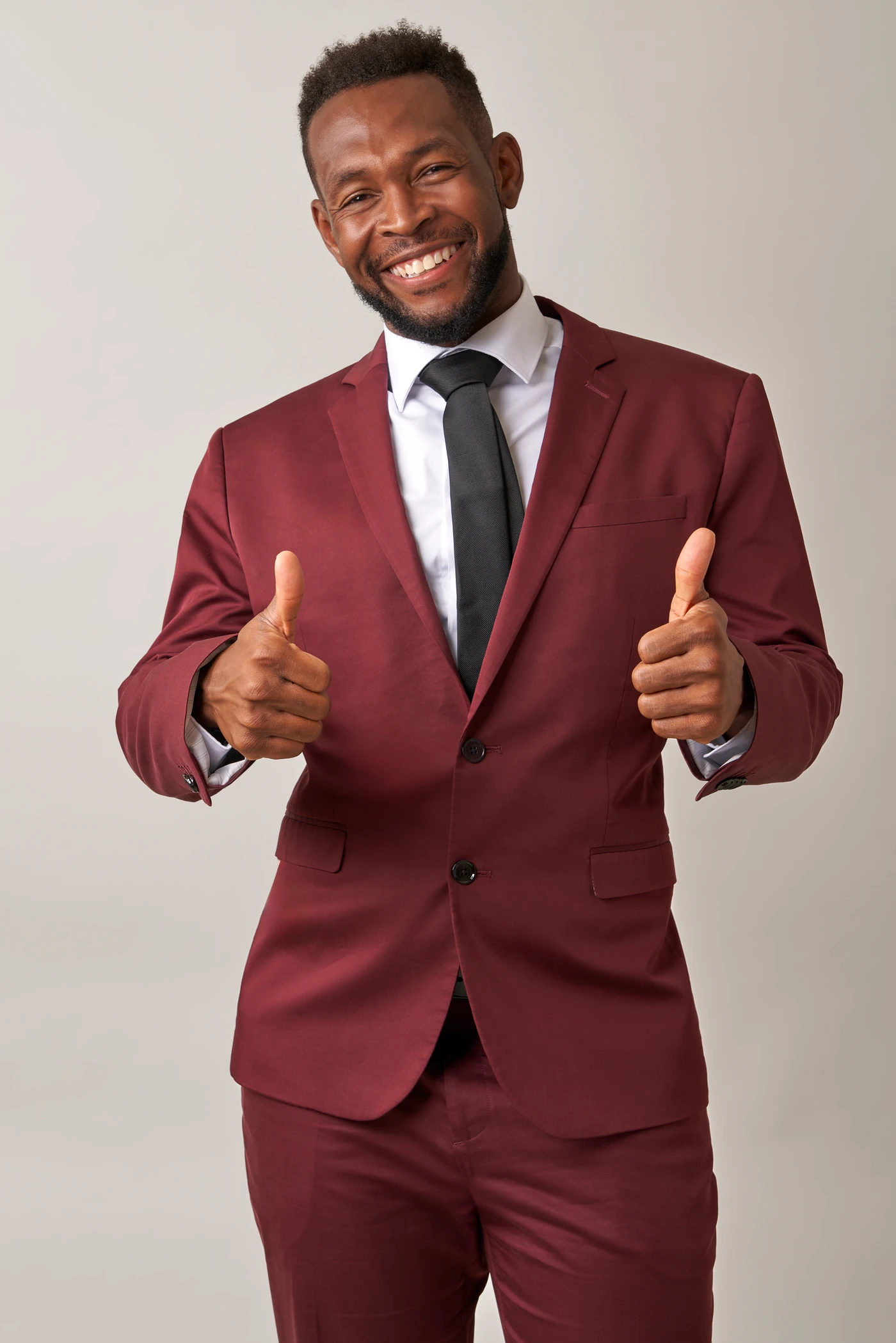 Malcolm Alexander-Neal smiling in a burgundy suit
